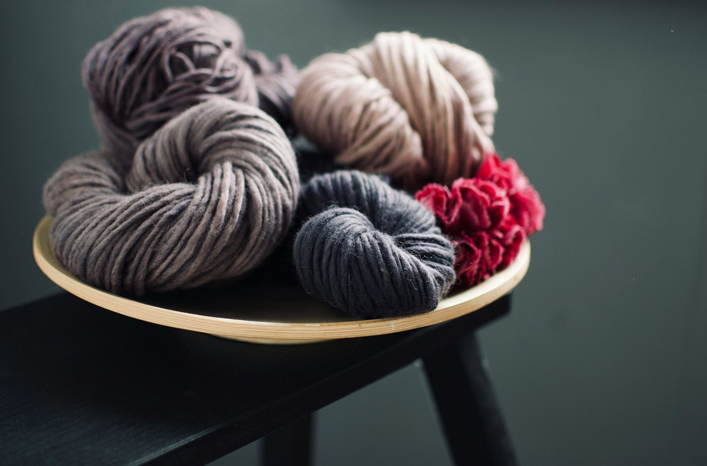 Colorful yarn skeins arranged on a wooden plate.