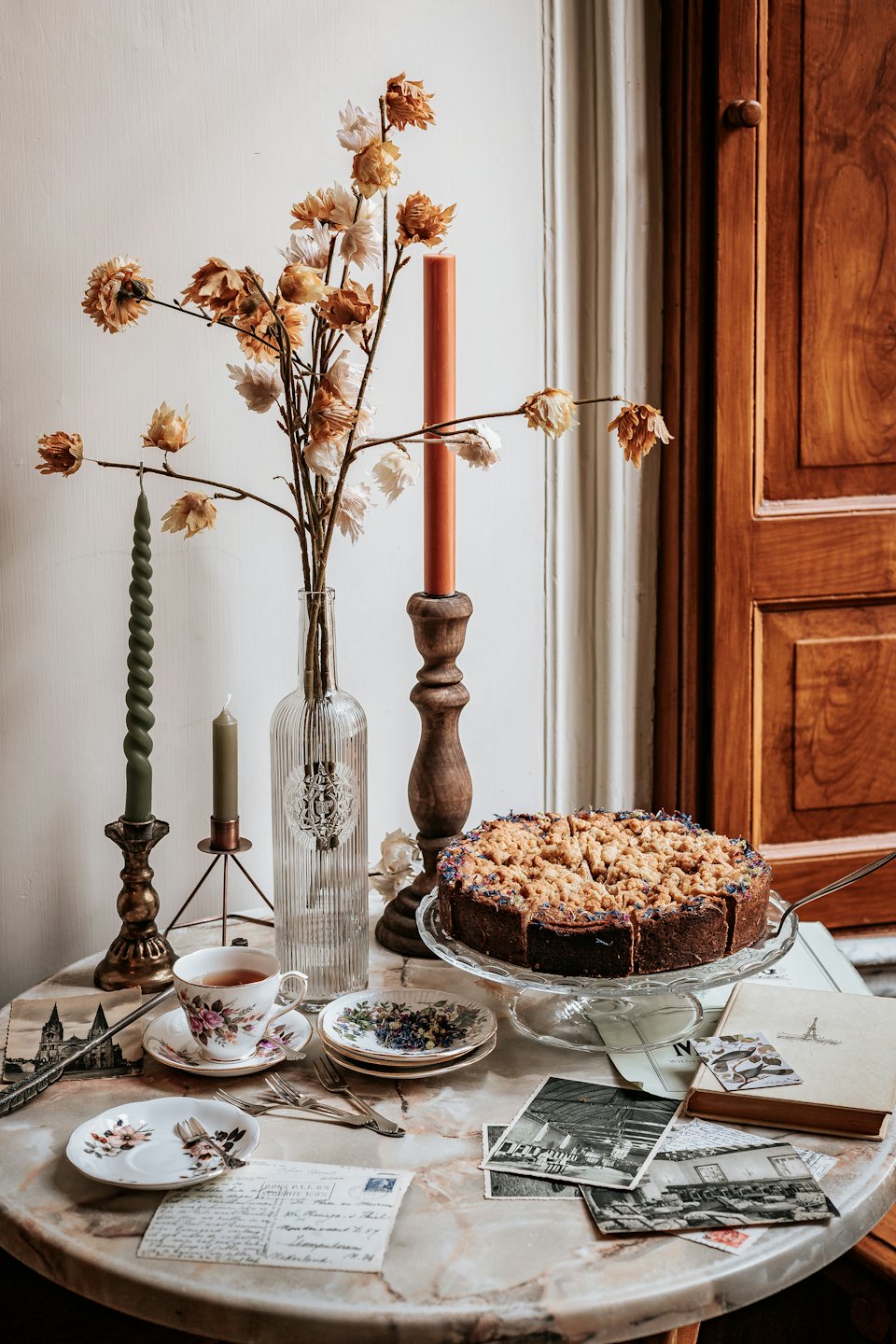 Marble table set with cake, teacup, and vintage decor.